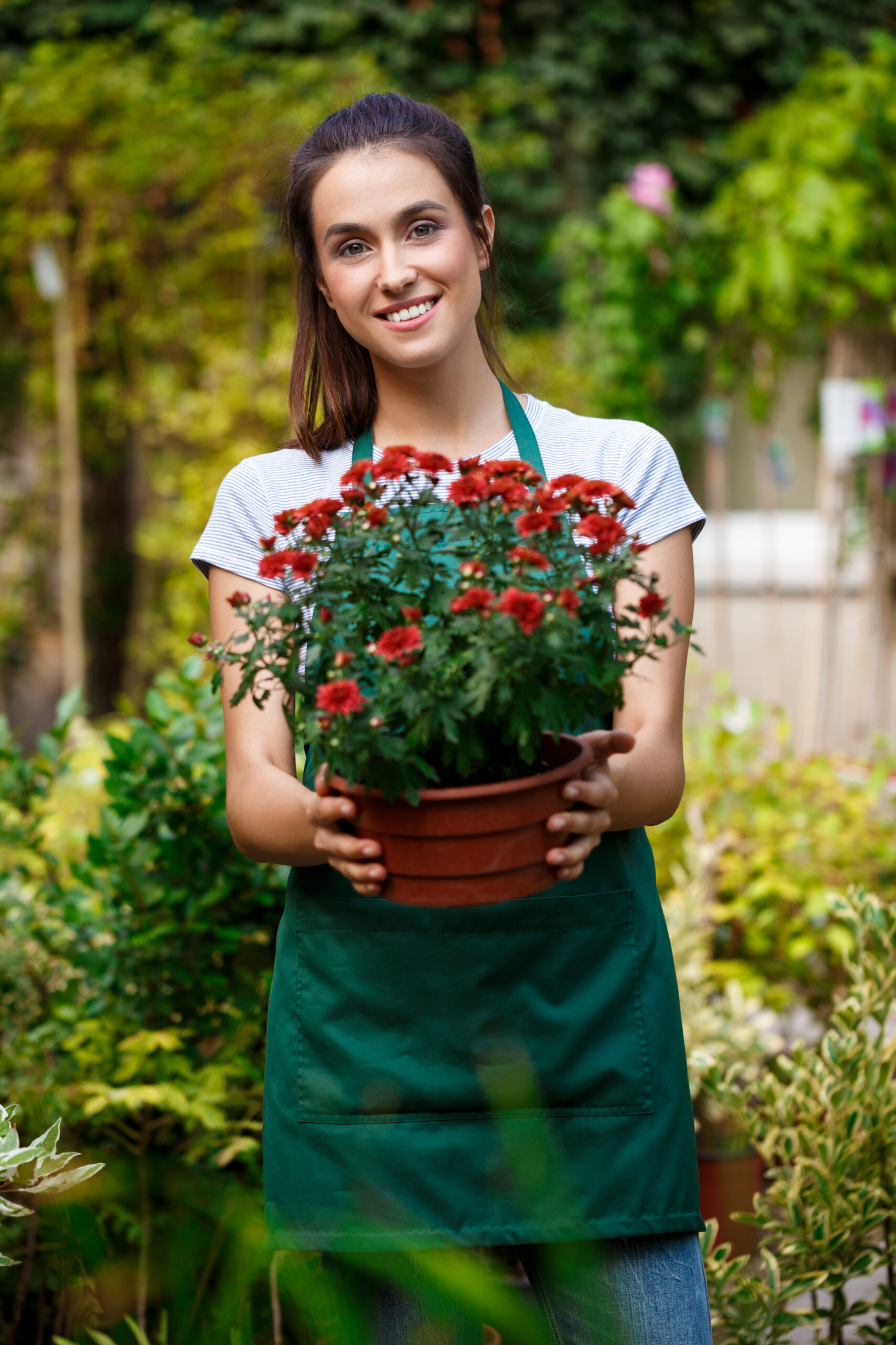 Young beautiful female florist posing, smiling among flowers.